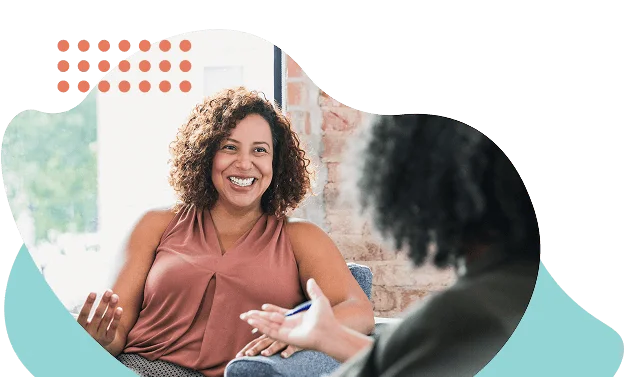 "Woman smiling and gesturing while talking with someone taking notes, framed by Clearpath's brand shapes."