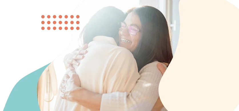 Two women embracing warmly, one smiling with eyes closed, framed by Clearpath's brand shapes and coral dot pattern.