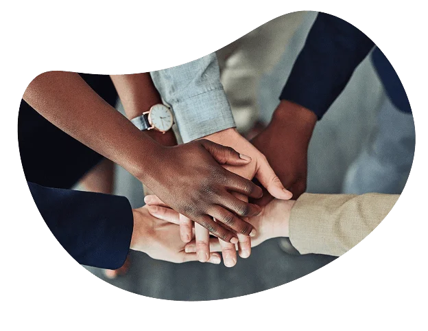 "Group of people in business attire stacking their hands together in a show of teamwork."