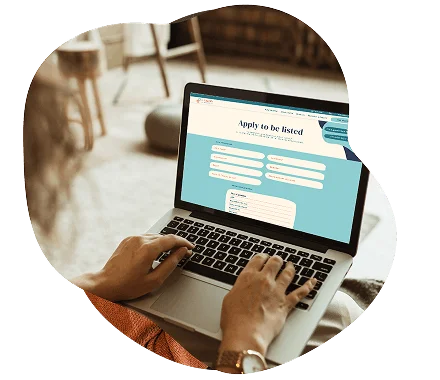 "Hands typing on a laptop displaying an 'Apply to be listed' form."