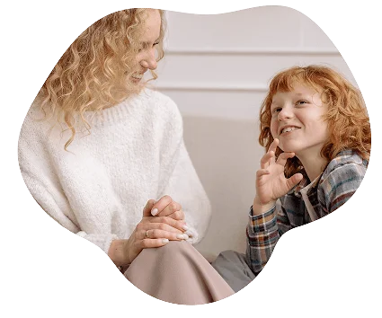 "Woman and young boy with curly red hair smiling and talking together."